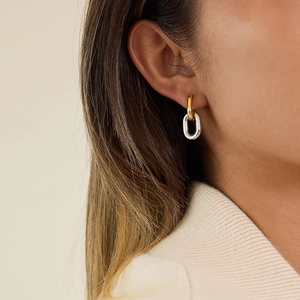 Minimalist two-tone oval hoop earrings in gold and silver finish worn by a model