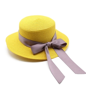 Détail d'un chapeau de paille jaune avec ruban violet et texture tressée pour l'été