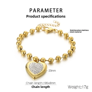 Détail du bracelet à billes en acier doré avec pendentif en cœur et cristaux