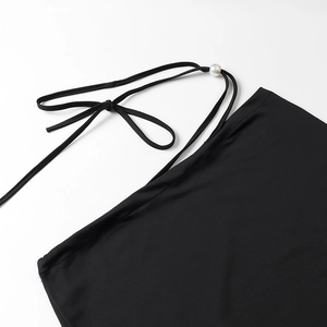 Detailed close-up of black knit fabric with white pearl drawstring and textured weave