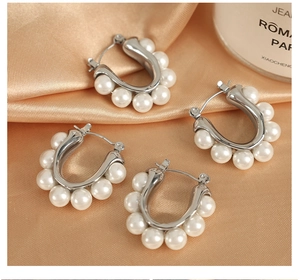 Detail of silver U-shaped hoop earrings with embedded pearls on champagne silk background