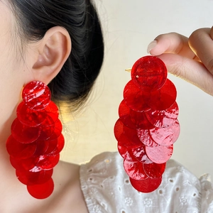 Close-up of vibrant red layered disk drop earrings on model for a bold French style