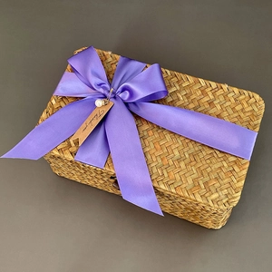 Detailed macro of seagrass woven gift box with a purple ribbon and thank you tag