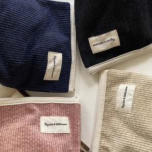 Flat lay of corduroy pouches in navy, black, pink, and beige with zip closures