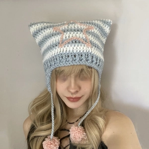 Close-up of blue and white striped knit cat ear hat featuring pink star patterns and pom-poms