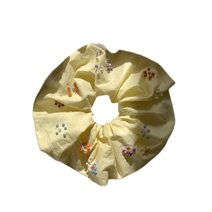 Elastico per capelli giallo fatto a mano con fiori di perline colorate su sfondo bianco