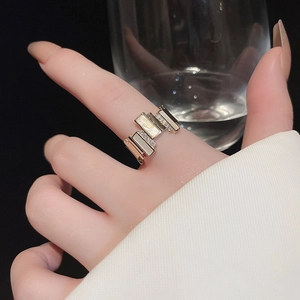Detail of gold plated geometric ring with cubic zirconia and white rectangular inlay