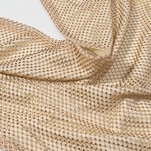 Gros plan sur un tissu en maille dorée avec des strass brillants pour robes de soirée