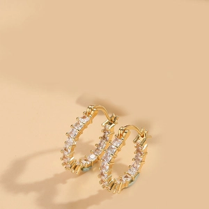 Detail of gold huggie earrings with pave-set square-cut cubic zirconia crystals