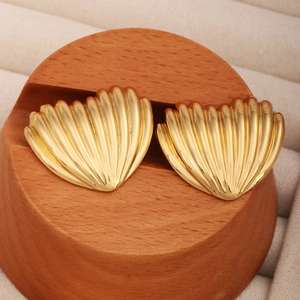 Détail de boucles d'oreilles cœur en plaqué or sur un support rond en bois