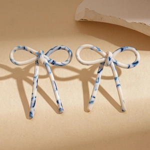 Detail of bow-shaped acetate earrings with blue and white marble pattern texture