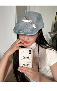Detail of light blue denim beret featuring silver bow and pink heart rhinestone decorations