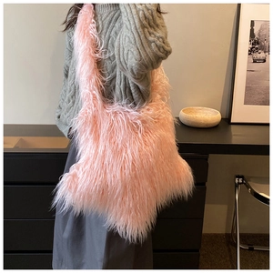 Chic pink faux fur shoulder bag worn by model over gray sweater for a cozy winter look