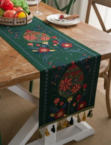 Detailed embroidered floral patterns and tassel trim on dark green Christmas table runner
