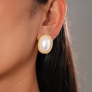 Detailed view of vintage pearl resin earrings with gold woven border on a model