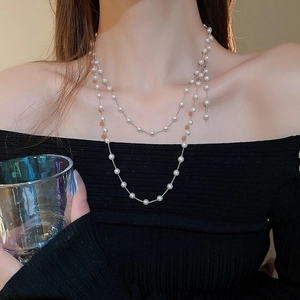 Gros plan d'un collier double rang en perles d'imitation porté sur un pull en maille noir