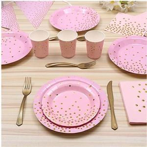Flat lay of pink party tableware set with gold dots including plates and cups