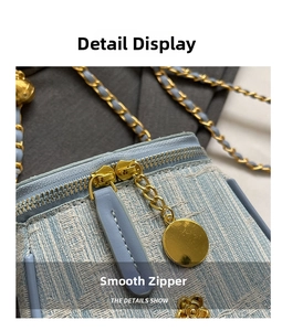 Detail of light blue tweed bag showing gold dual-zipper closure and floral metal charm