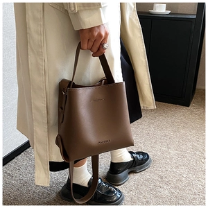 Detailed view of the vintage brown bucket bag being carried by a model in a modern room