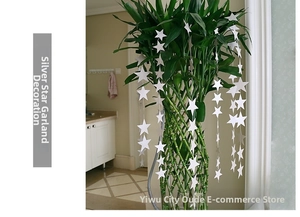 Close-up of reflective silver star garland hanging on a plant for party decoration