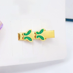 Macro detail of golden hair clips with green striped butterflies on a display card
