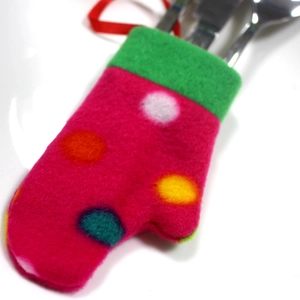 Close-up of rose red felt Christmas glove cutlery holder with fork and knife on white