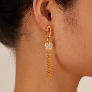 Macro shot of gold-plated tassel earrings featuring a diamond-set floral charm and chain