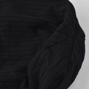 Dettaglio del berretto in maglia nera con trama a costine e tessuto morbido premium