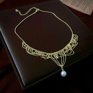 Detail of vintage gold bead lace necklace with a white pearl pendant and adjustable chain