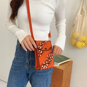 Close-up of orange knitted mini crossbody phone bag with black snake pattern and flap
