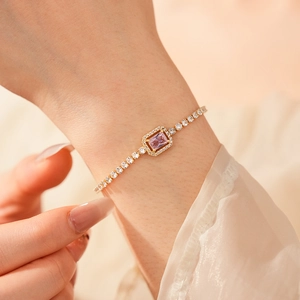 Close-up of golden adjustable bracelet with pink zircon stone on woman wrist