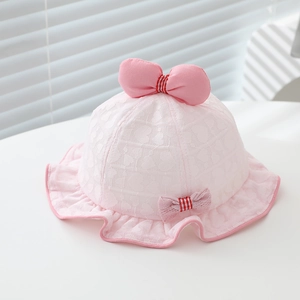 Détail d'un chapeau de soleil en dentelle rose pour bébé avec un grand nœud élégant