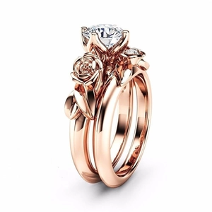 Vista dettagliata del set di anelli impilabili in oro rosa con design floreale e zircone