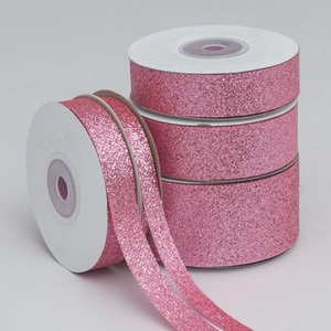 Detail of four rolls of pink glitter polyester ribbons for festive gift wrapping decor