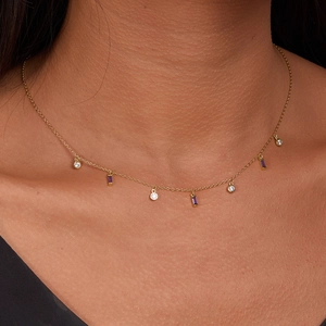 Detail of gold necklace with square purple stones and round white zircons on skin