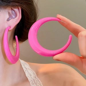 Detail view of large hot pink crescent hoop earring showing glossy finish and bold curve