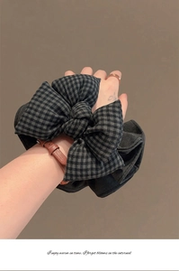 Gros plan du chouchou nœud vichy noir et gris au poignet avec détail du tissu brodé