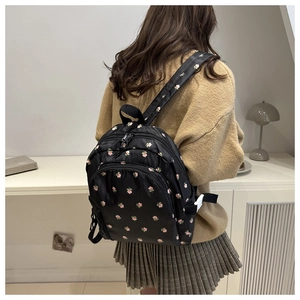 Detailed back view of a black floral backpack with pink flowers on a female model