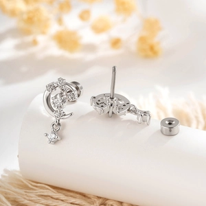 Silver star and moon earrings with clear zircons and screw back on a white display pedestal