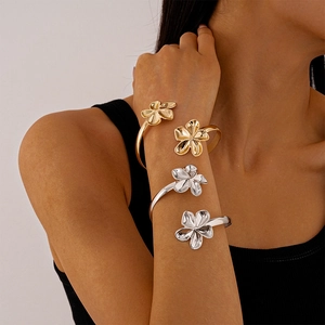 Minimalist metallic flower arm cuffs in gold and silver finish stacked on a model