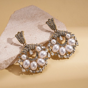 Detail of vintage gold drop earrings with pearls and diamonds on stone stand