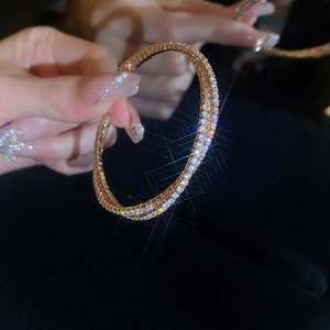 Macro shot of rose gold double-layer zircon crisscross bracelet on a dark background