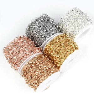 Macro detail of bead link chains in 5 metallic colors on white plastic spools