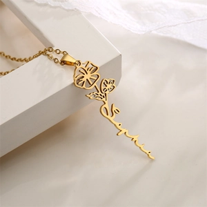 Close-up of gold-plated stainless steel birth flower name necklace on white display stand