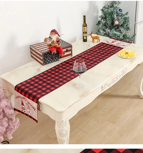 Detail of red and black plaid Christmas table runner with festive gnome motif on marble table