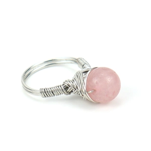 Macro detail of handmade silver wire wrapped ring featuring a rose quartz crystal bead