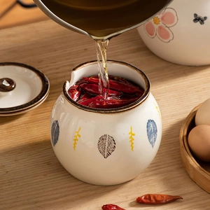 Ceramic lard jar with floral pattern and lid, pouring hot oil over dry chili peppers