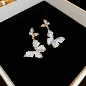 Gros plan de boucles d'oreilles papillon avec cristaux blancs et dorure sur velours