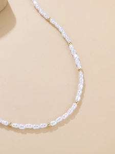 Detail of irregular white baroque pearls alternating with gold metal beads on a necklace