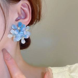 Elegant blue acrylic flower earrings with faux pearls shown on a model's side profile